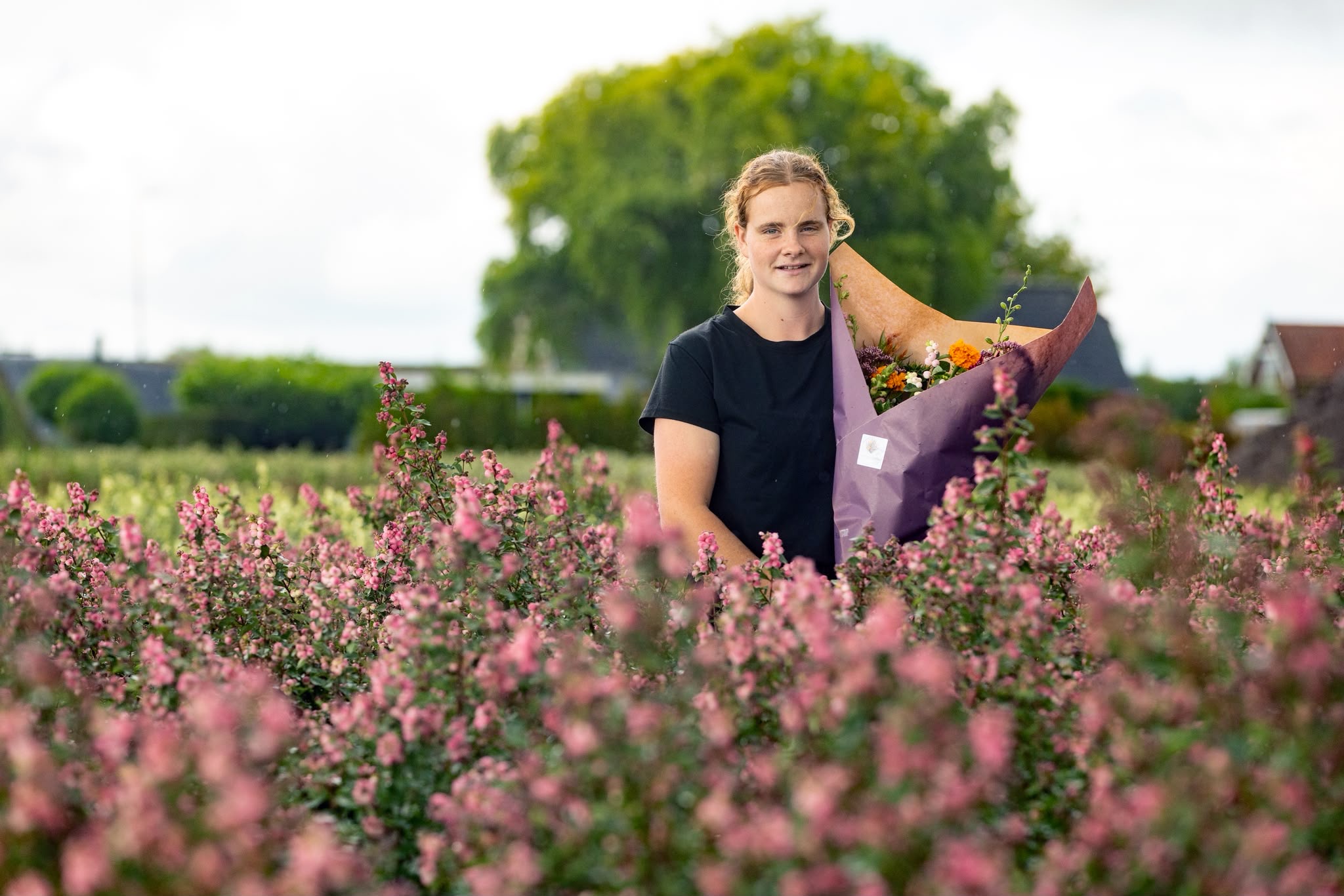 Alida van Bloemenhofke met een boeket in een bloemenveld
